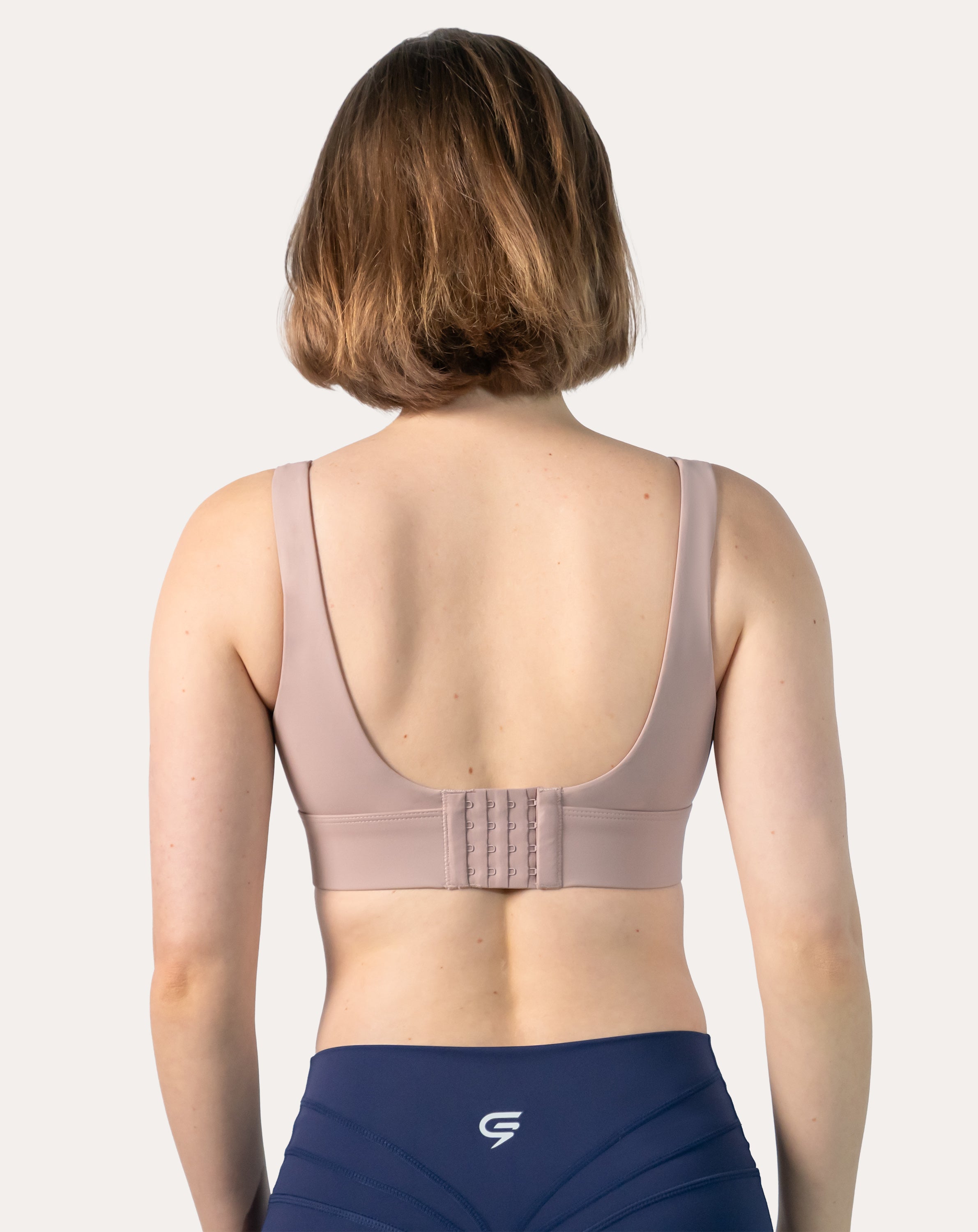 Back view of baby pink sports bra showing hook-and-eye closure and U-back