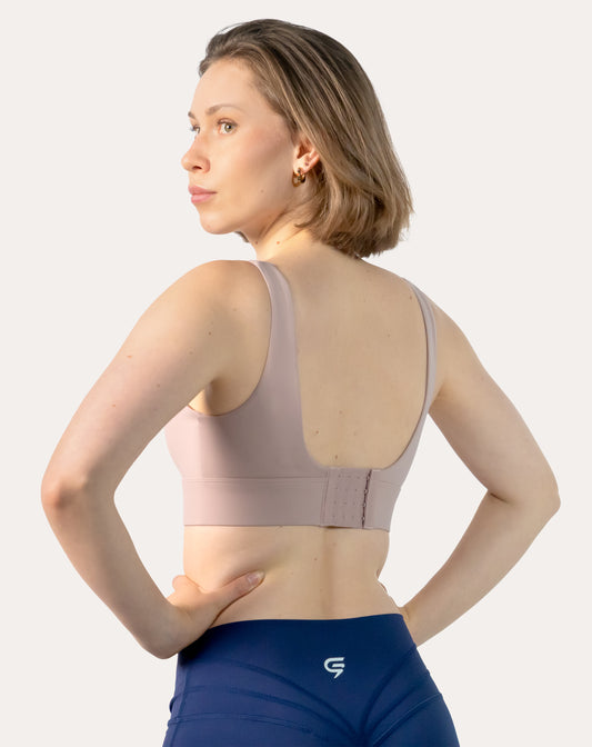 Back three-quarter view of baby pink sports bra highlighting deep U-back with adjustable hook-and-eye