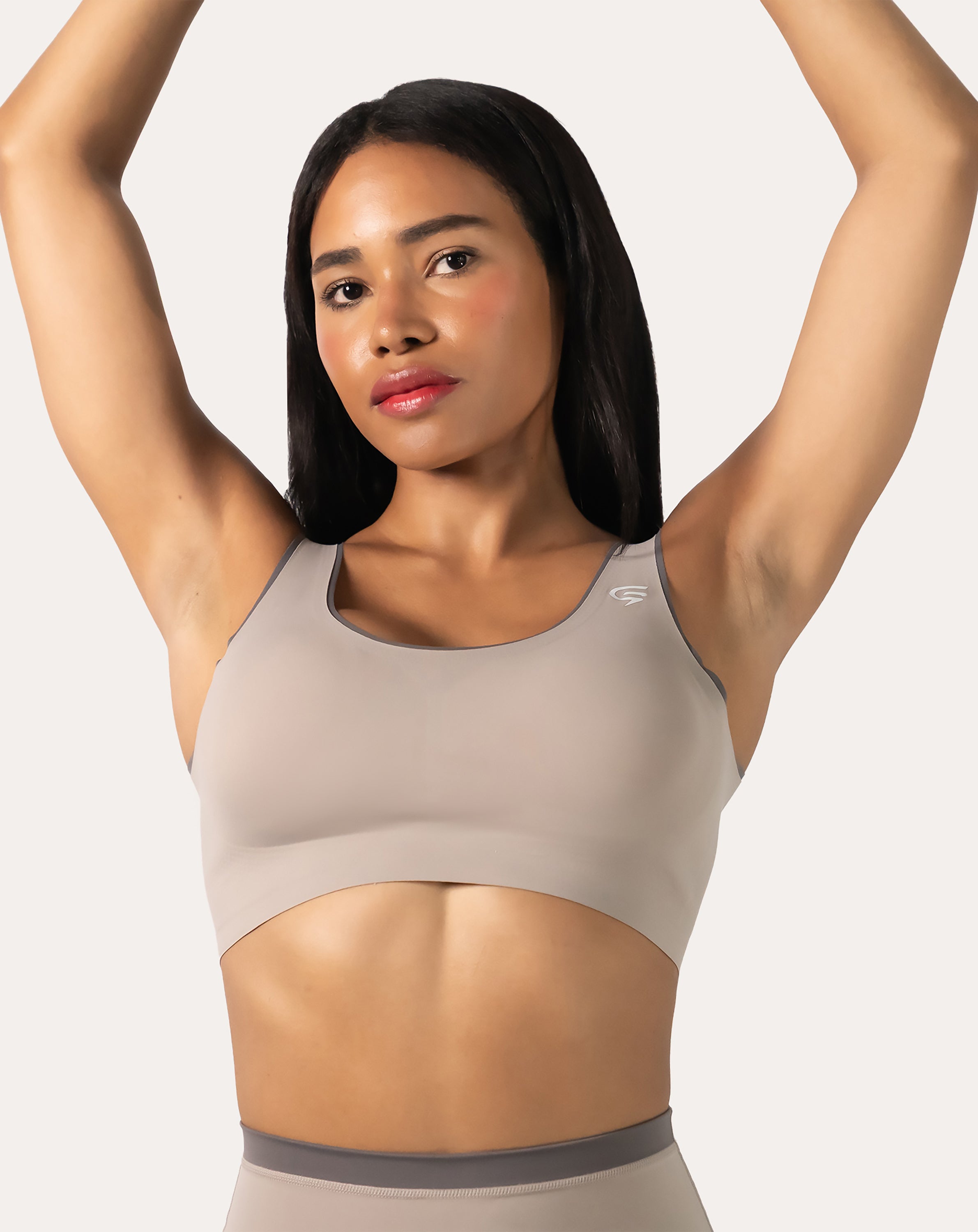 Beige high impact sports bra, front view with arms raised to show strap placement