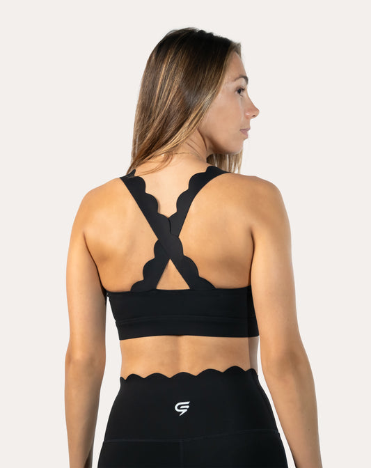 Back three-quarter view of black padded sports bra with cross-back scalloped straps