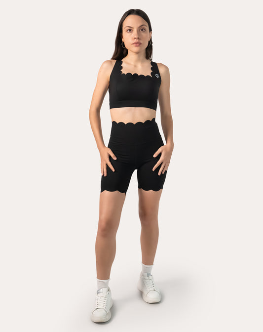 Full-body front view of black workout shorts with scalloped high waist and biker length