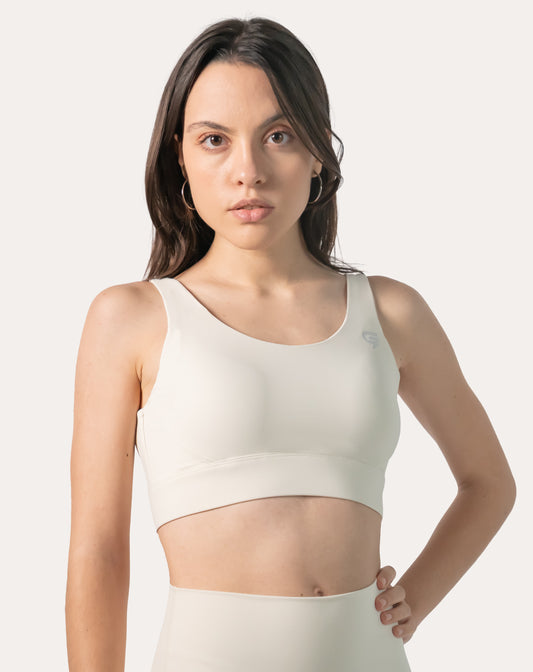 Straight-on front, mid-length view of the cream supportive sports bra with wide straps and smooth band