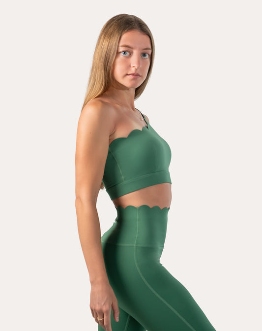 Side profile showing emerald green gym set with one-shoulder longline bra and sculpting leggings