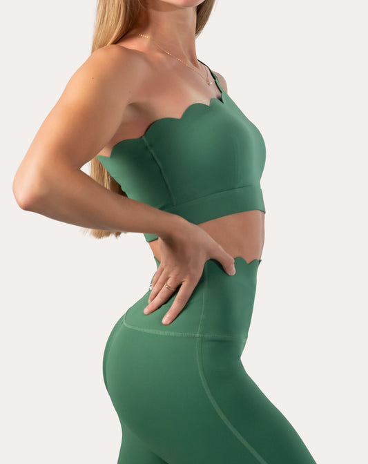 Left side view of green sports bra showing one-shoulder fit and wide underband