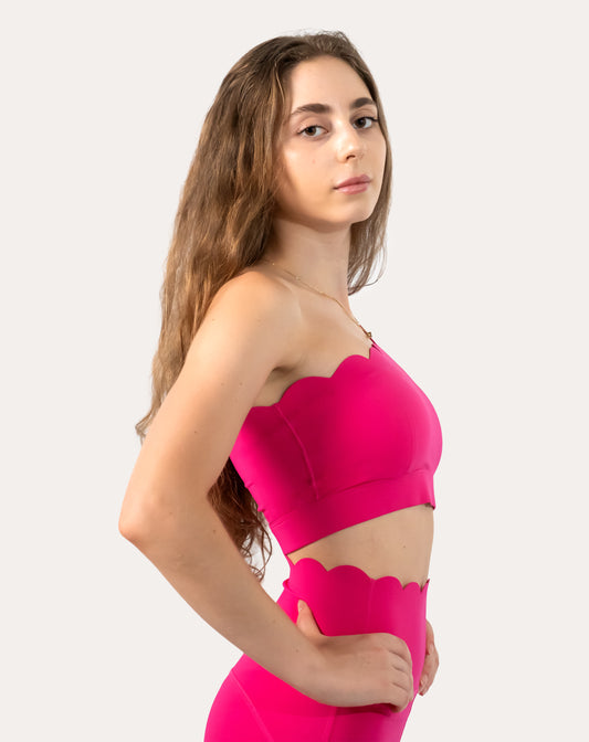 Left three-quarter view showing one-shoulder strap and wide underband on hot pink sports bra