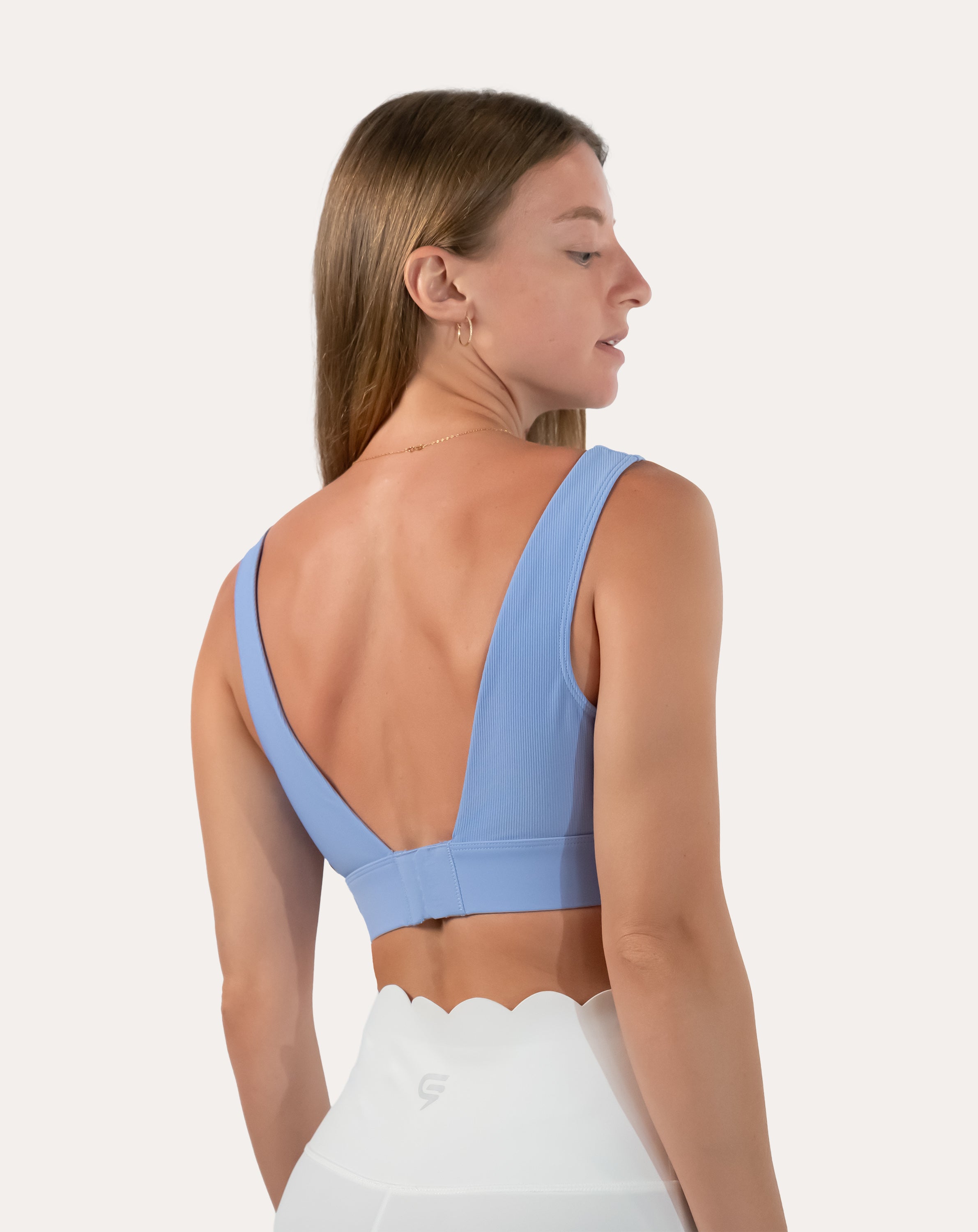 Left back three-quarter view of light blue square neck sports bra with deep V hook-back closure