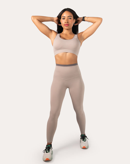 Front view with arms raised showing the light grey gym set’s scoop bra and smooth high-waist leggings