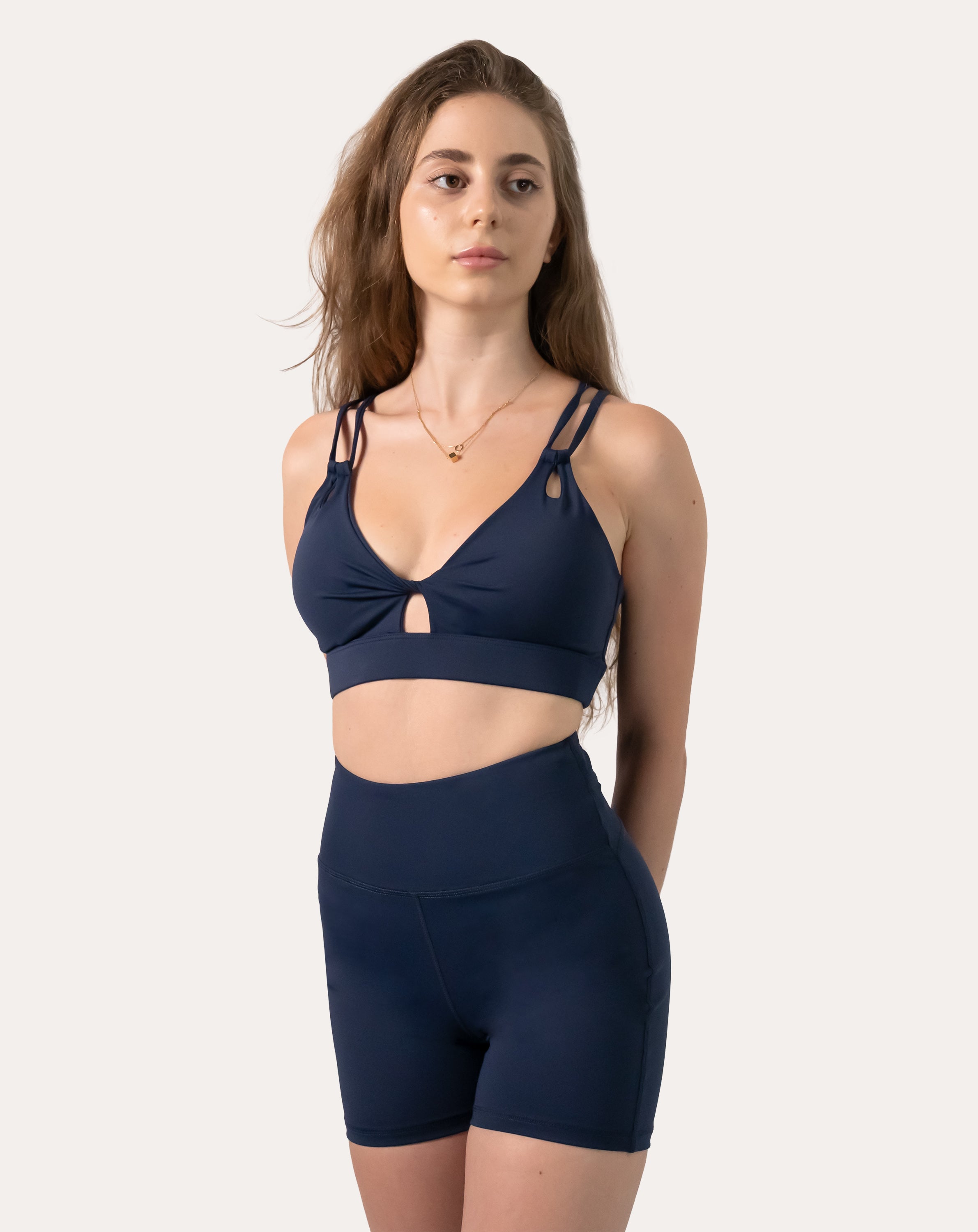 Navy sports bra full-length front view highlighting V-neck, small keyhole and wide underband
