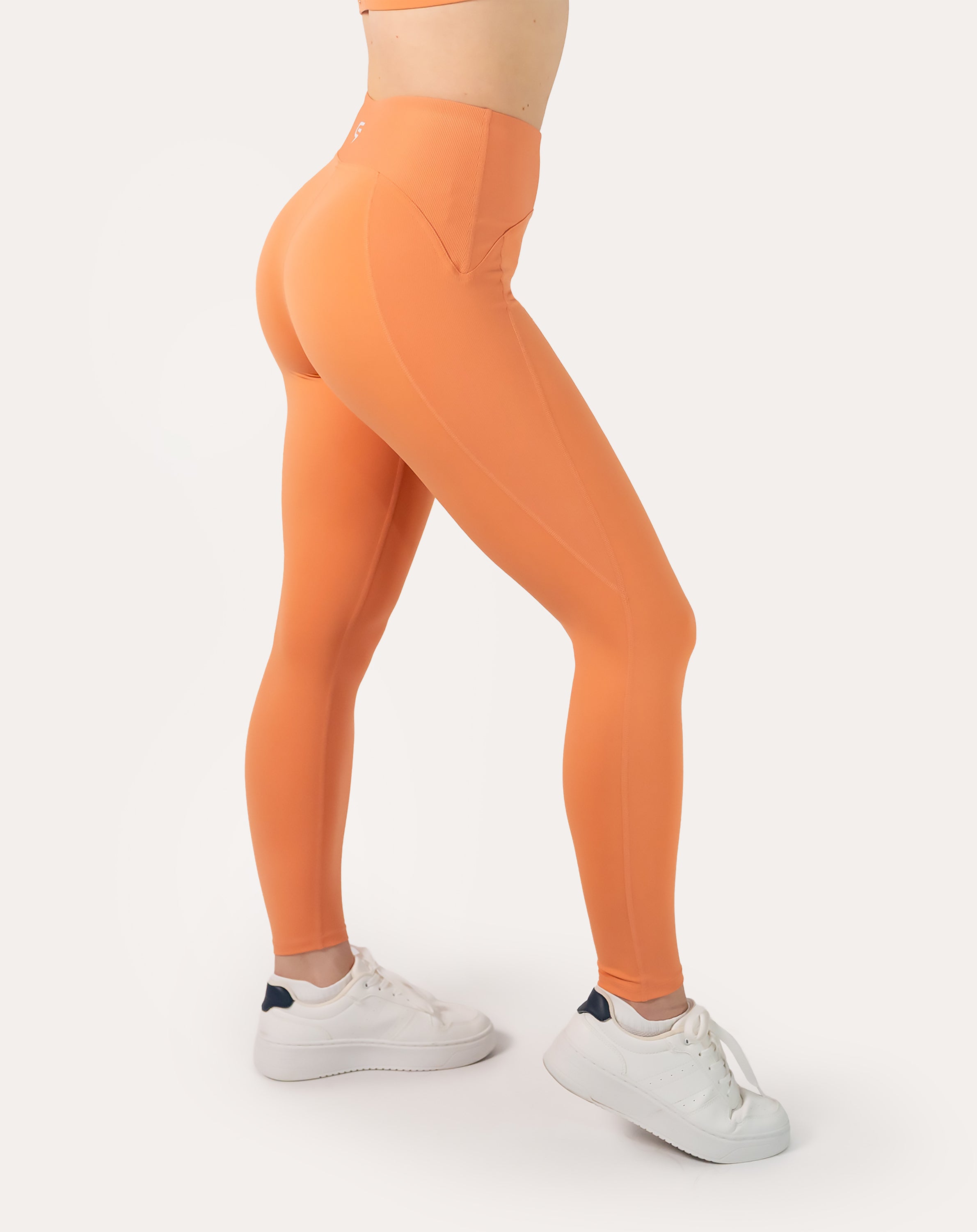Side detail of orange gym set leggings highlighting high-waist fit and smooth seams