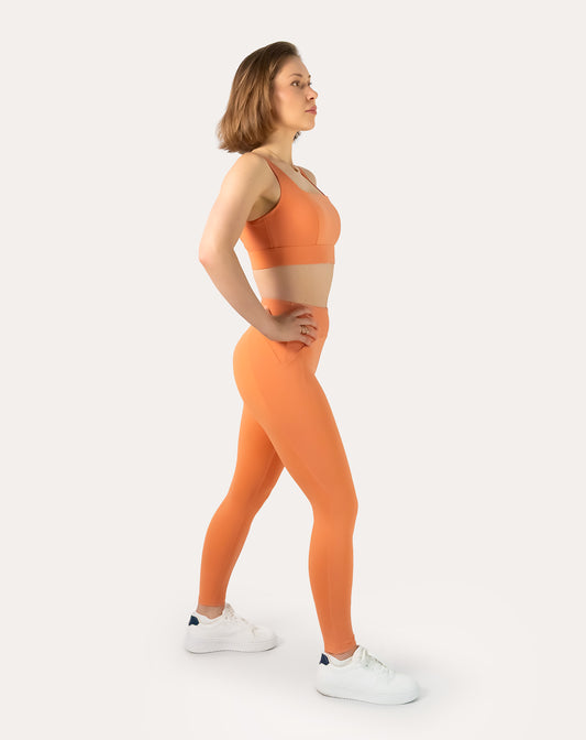 Side profile of orange gym set showing square-neck bra and sculpting high-waist leggings