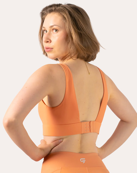 Left back three-quarter view of orange sports bra with deep V, hook-and-eye back closure