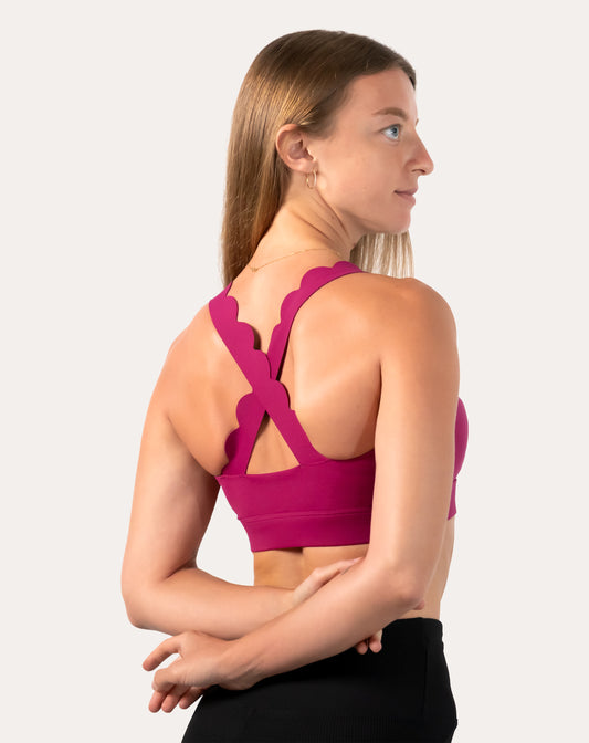 Back three-quarter right view of pink sports bra highlighting crisscross straps