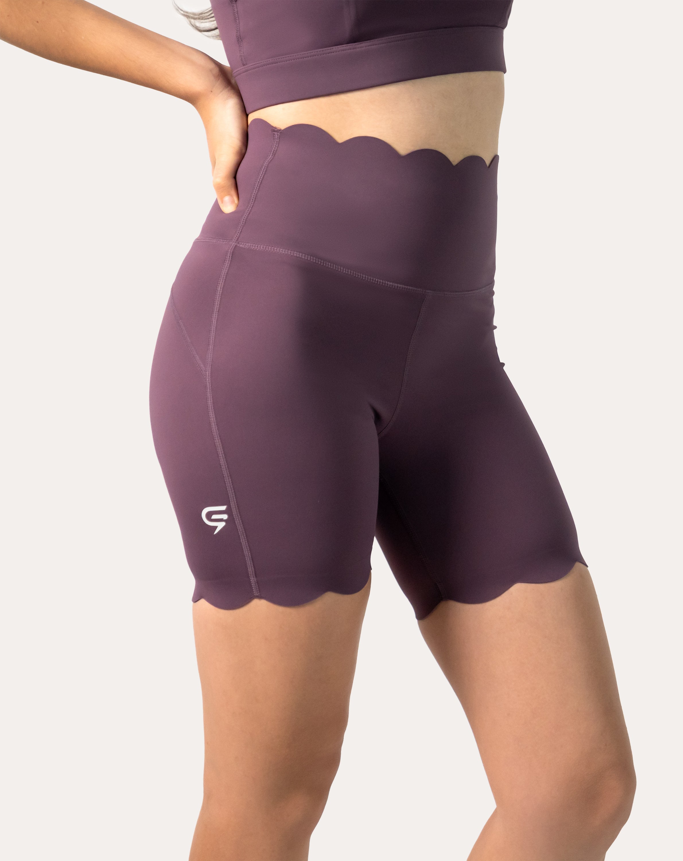 Side close-up of plum high-rise biker shorts from the one-shoulder gym set with smooth seams and logo