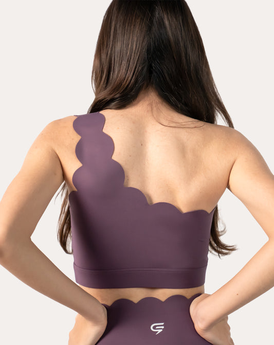 Close-up of back on the plum one-shoulder gym set top showing scallop edges and longline cut
