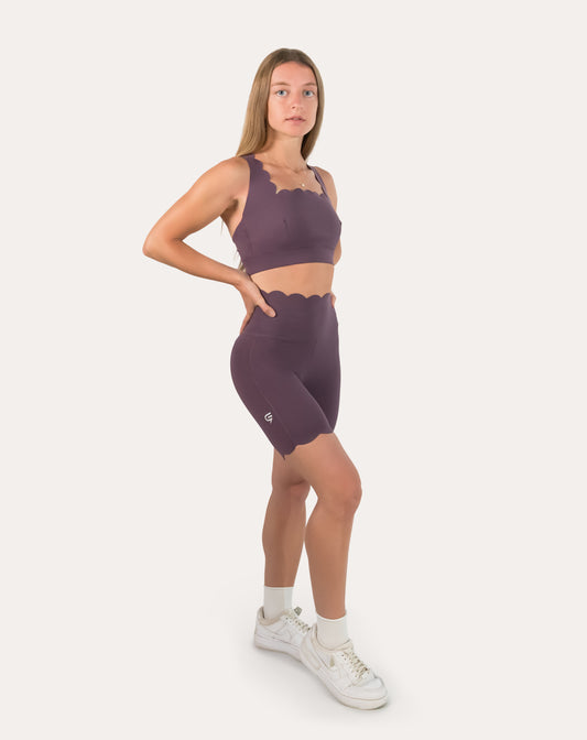 Purple gym set in three-quarter front pose showing longline bra and biker shorts fit