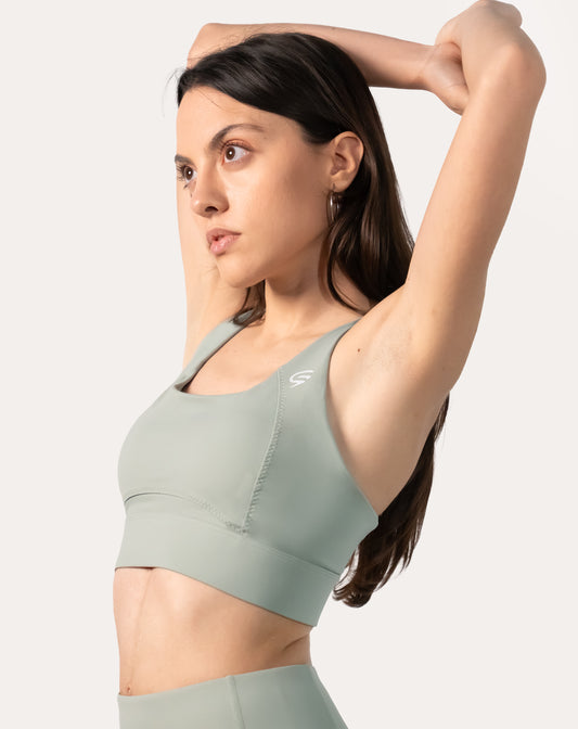 Sage green running sports bra side profile with one arm raised to show strap fit
