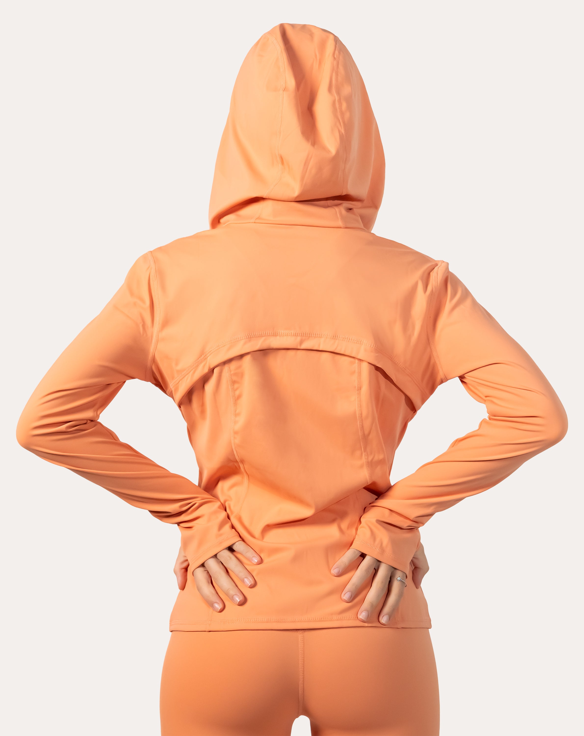 Back view of apricot women’s zip-up jacket with hood up and vented back yoke
