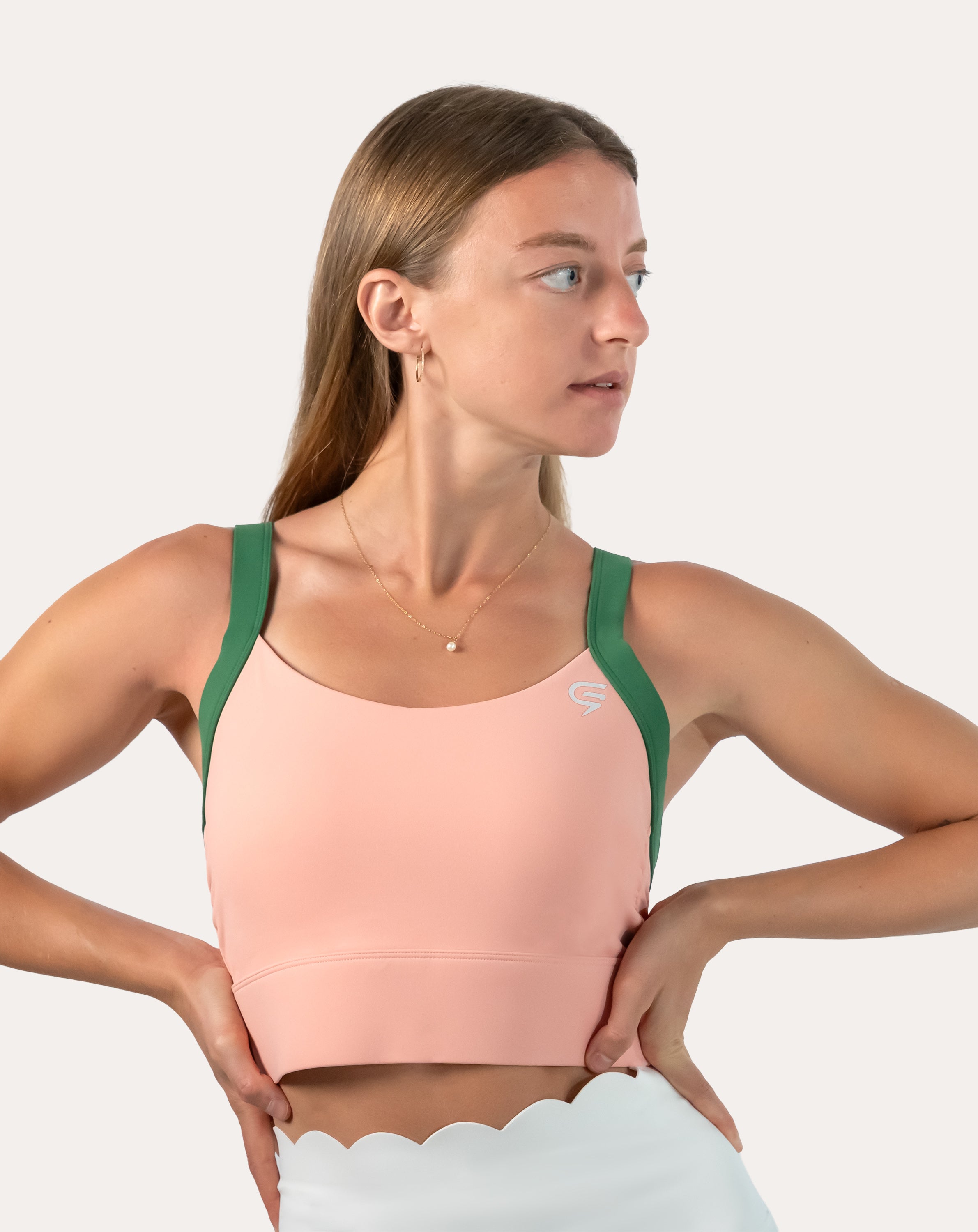 Side profile of peach and green yoga sports bra with wide green straps and longline hold.