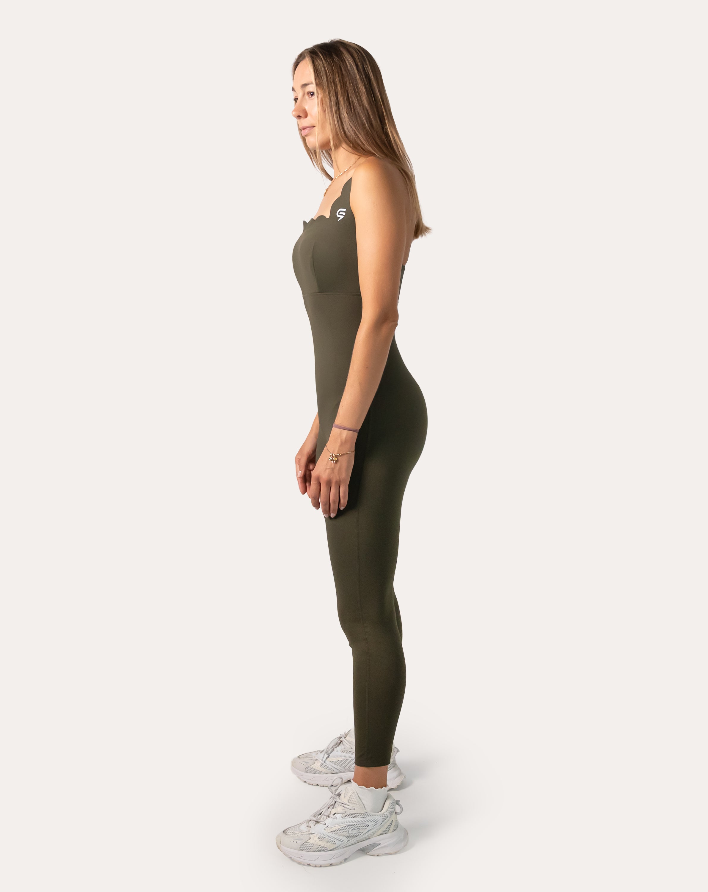 Left-side full-length view of olive athletic jumpsuit for women with sleek tapered legs