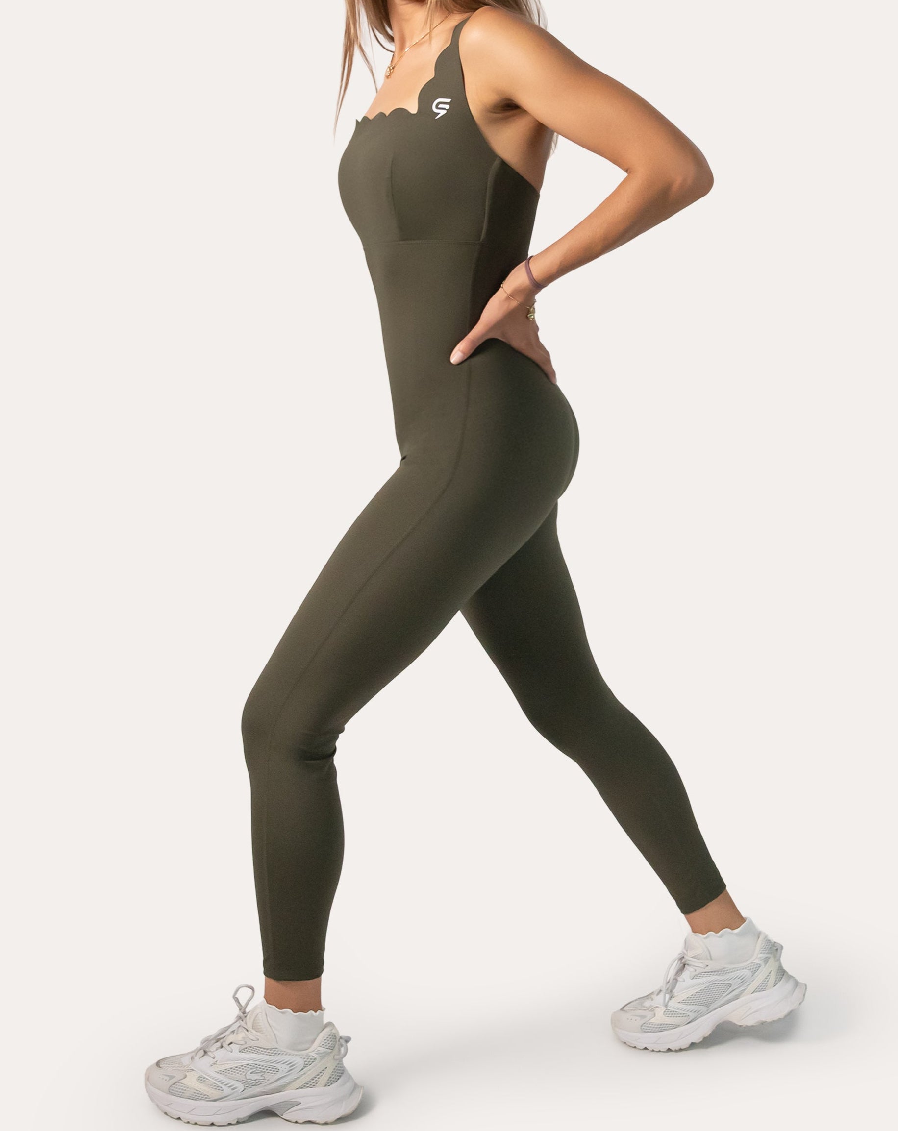 Right-side profile of olive athletic jumpsuit for women highlighting streamlined leg and hip