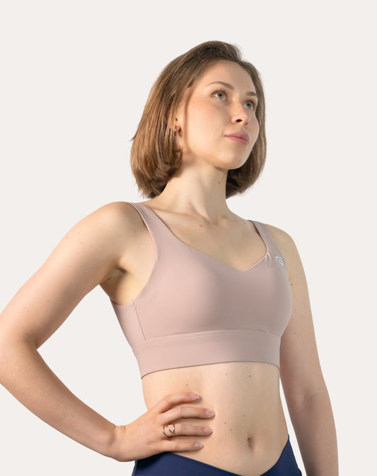 Baby pink sports bra, front three-quarter close-up with wide straps and smooth wireless front
