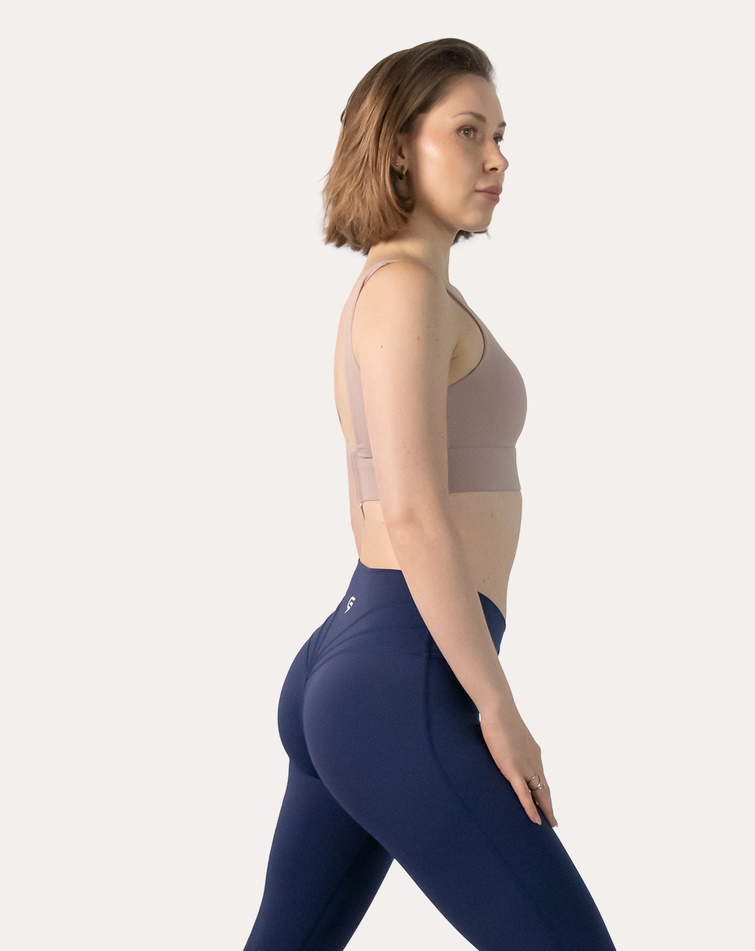 Side profile of baby pink sports bra showing wide straps and stabilising underband