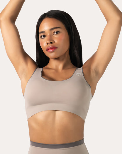 Beige high impact sports bra, front view with arms raised to show strap placement