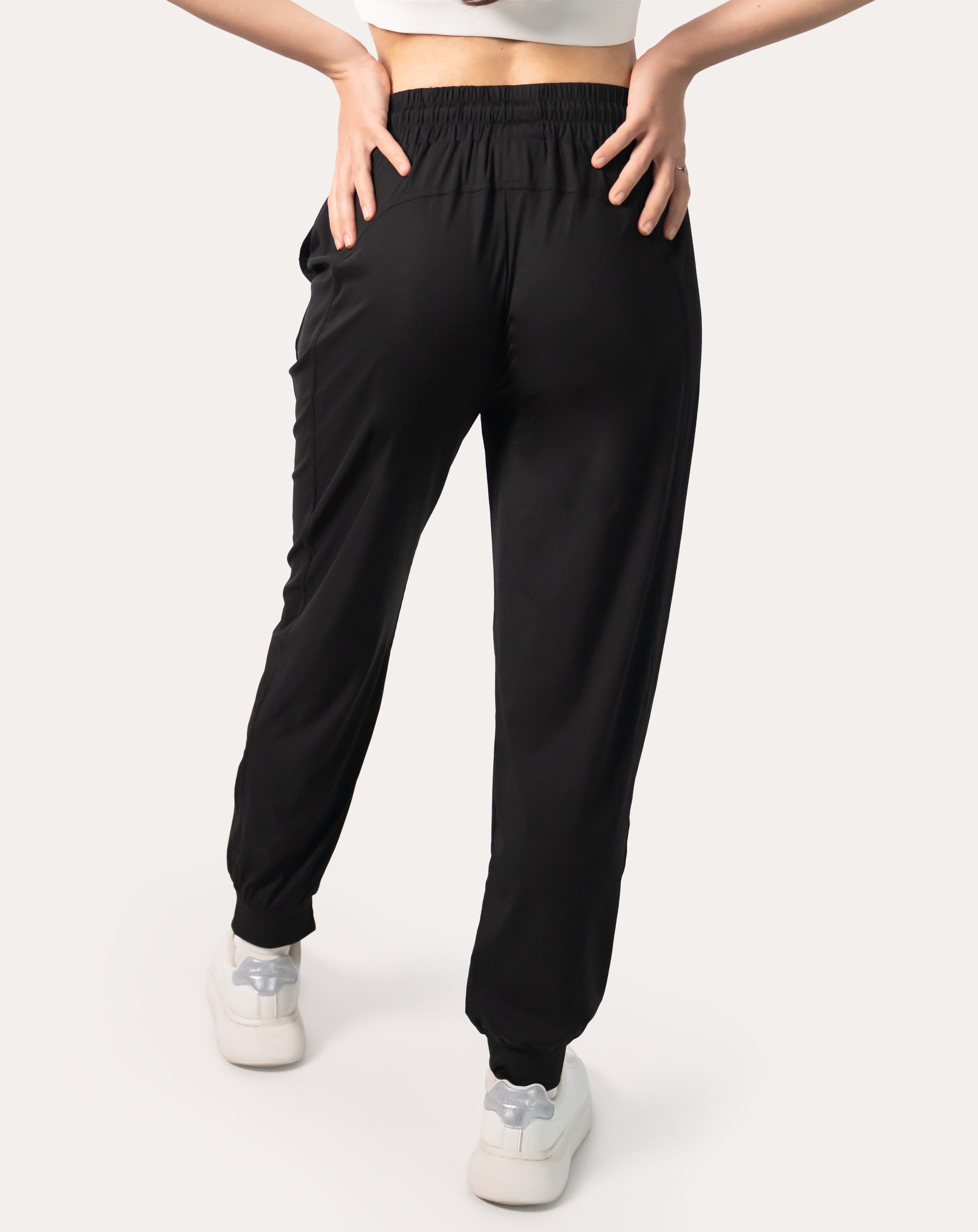 Back full-length view of black joggers for women with elastic waistband and cuffed ankles