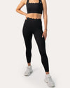 Full outfit front view pairing a scallop sports bra with matching high-waist black leggings for a gym-to-street look