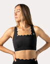 Right front three-quarter view of black padded sports bra featuring a scalloped neckline