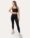 Three-quarter front view of black seamless gym set showing scallop neckline and legging fit