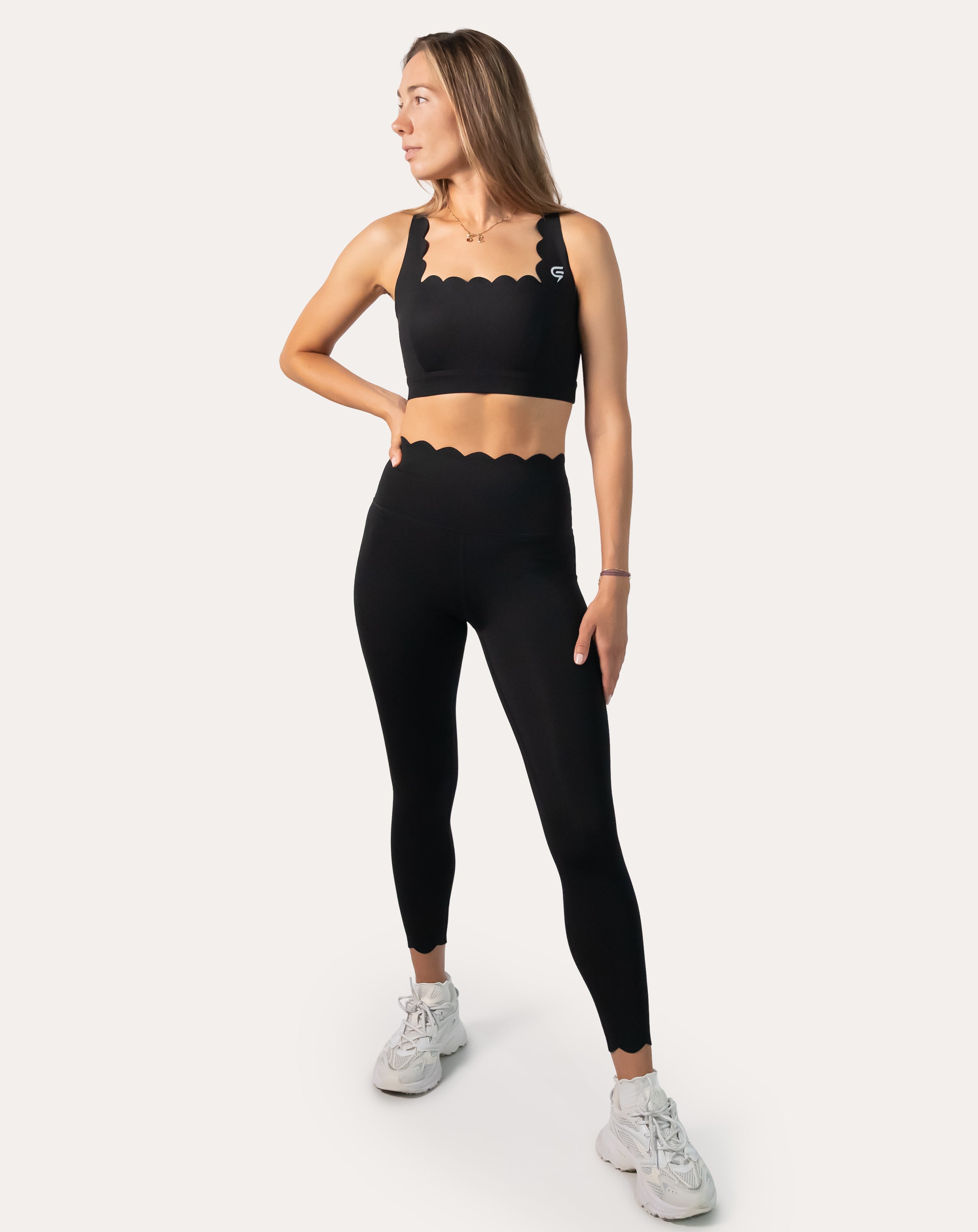 Three-quarter front view of black seamless gym set showing scallop neckline and legging fit