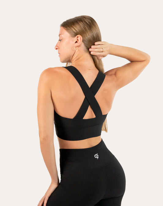 Left back three-quarter view of black sports bra with cross-back straps and seamless knit