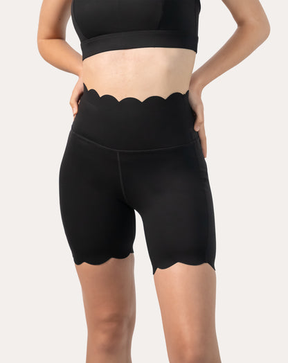 Front close-up of black workout shorts highlighting scalloped hem and high-waist band