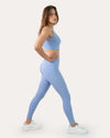 Blue gym set in three-quarter side step showing supportive bra and legging fit