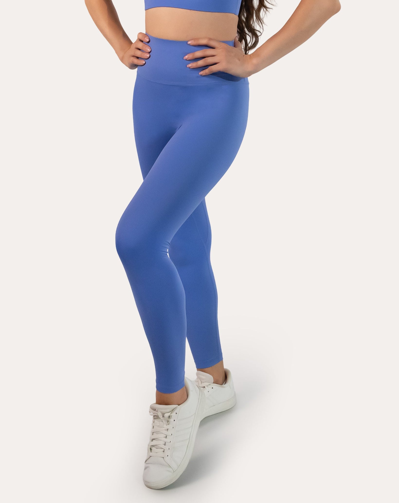 Model in matching cobalt blue sports bra and high-waist leggings, three-quarter pose; sleek gym set
