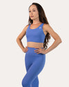 Full-length three-quarter front view of the blue sports bra showing scoop front and fit