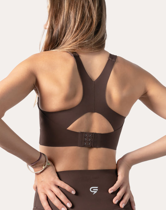 Close-up back of racerback bra on brown gym set showing hook-and-eye clasp and keyhole