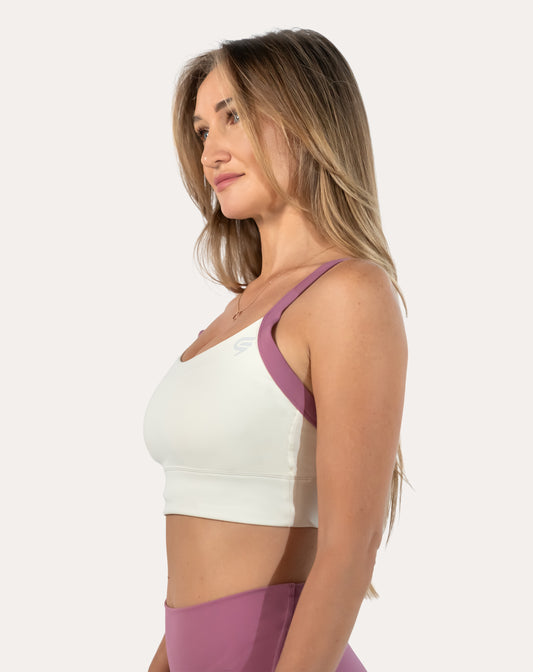 White/lilac women’s sports bra, three-quarter side close-up showing longline band and wide straps