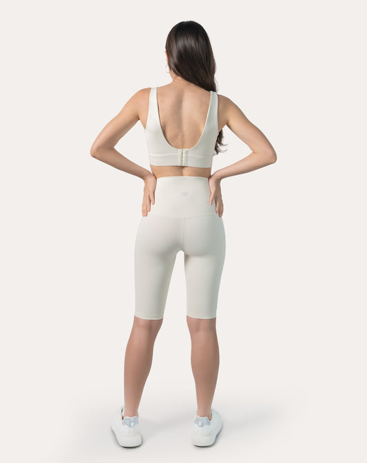 Back view of cream gym set showing clasp-back sports bra and high-waist biker shorts