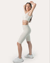 Cream gym set side view: clasp-back sports bra with high-waist biker shorts on model