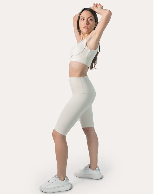 Cream gym set side view: clasp-back sports bra with high-waist biker shorts on model