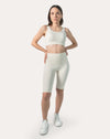 Front view of women’s cream gym set: scoop-neck sports bra and high-waist biker shorts