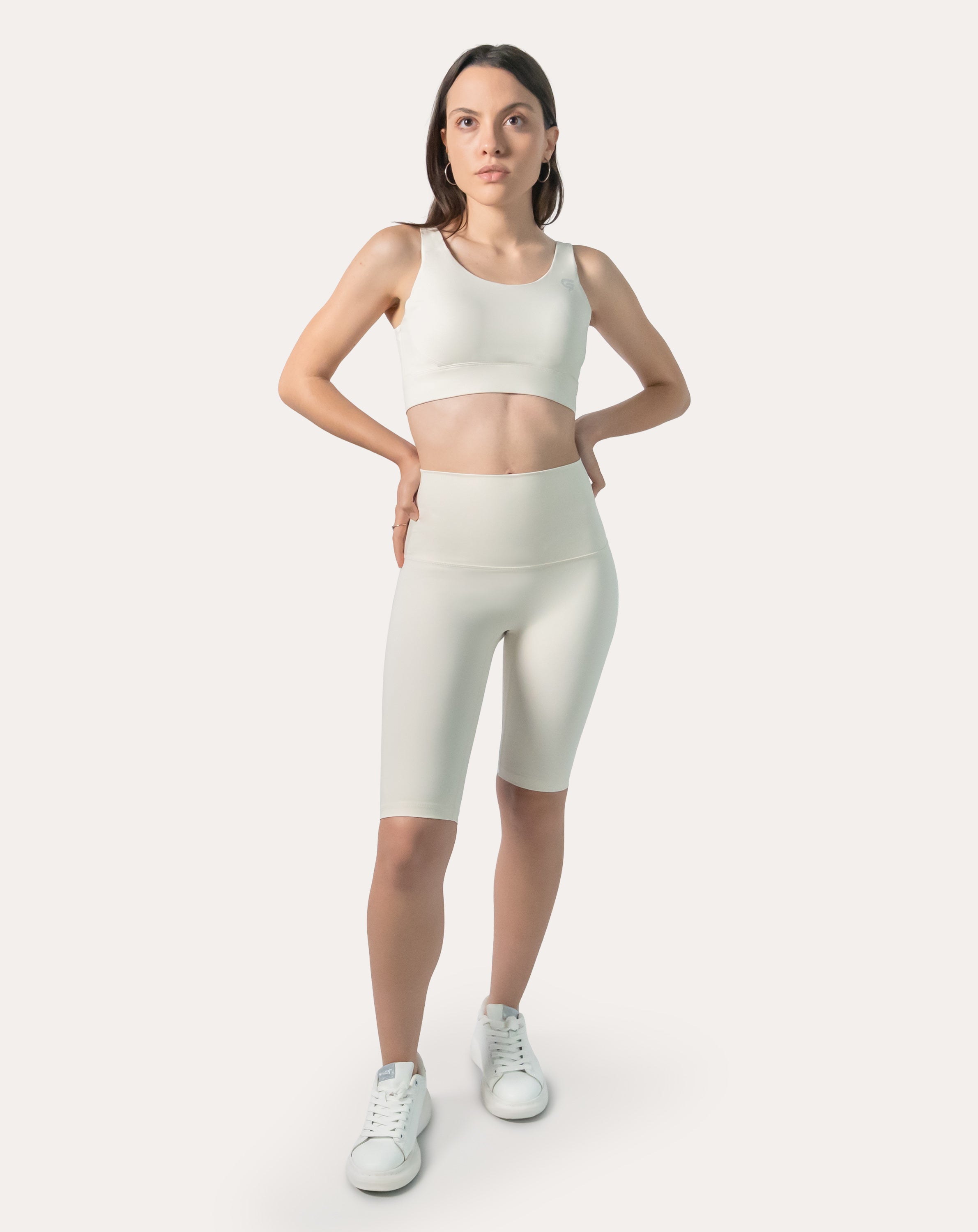 Front view of women’s cream gym set: scoop-neck sports bra and high-waist biker shorts