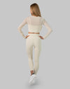 Back view of cream long sleeve gym set showing sheer mesh crop and smooth high waist leggings