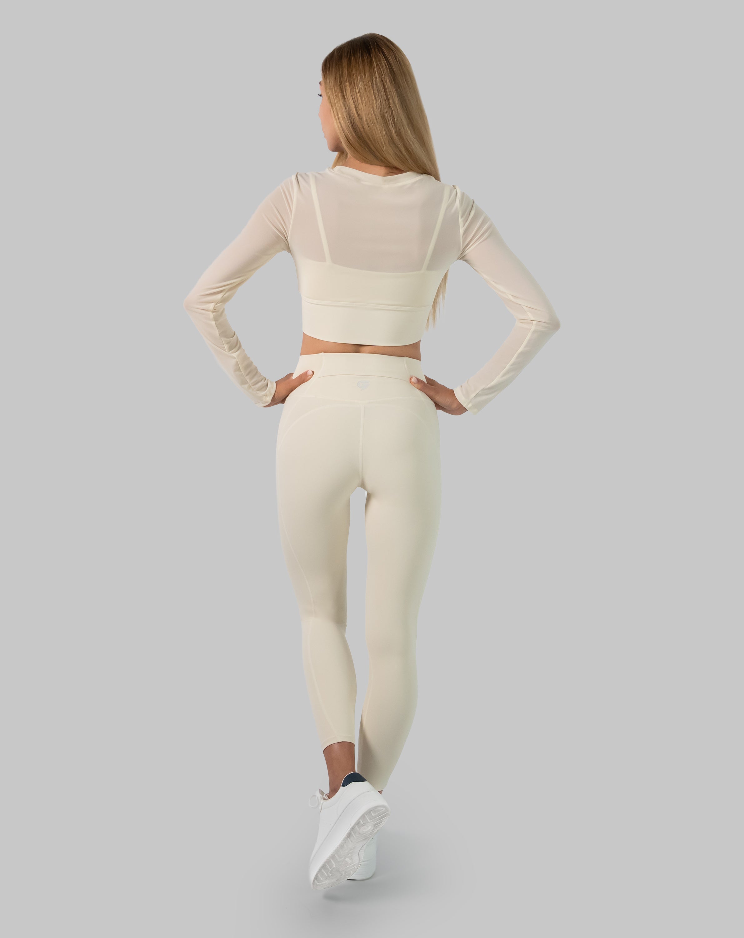 Back view of cream long sleeve gym set showing sheer mesh crop and smooth high waist leggings