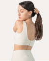 Three-quarter back view of the cream supportive sports bra showing U-back and longline band