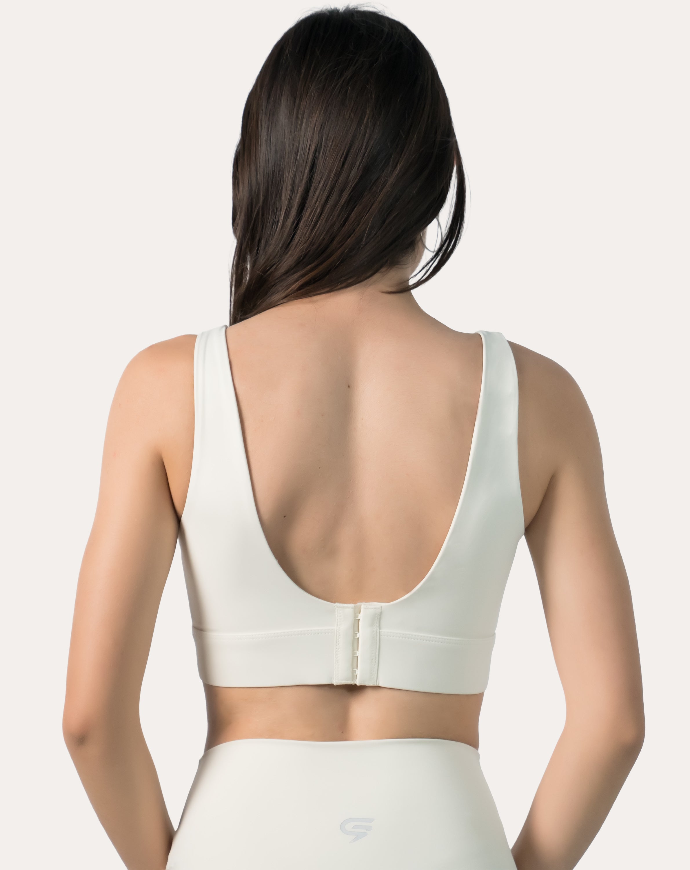 Back view of cream supportive sports bra highlighting deep U-back and hook-and-eye closure