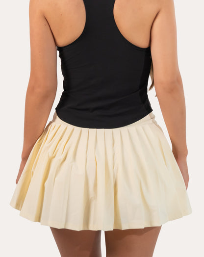 Back close-up of cream tennis skirt showing pleated mini hem and wide high-waist band