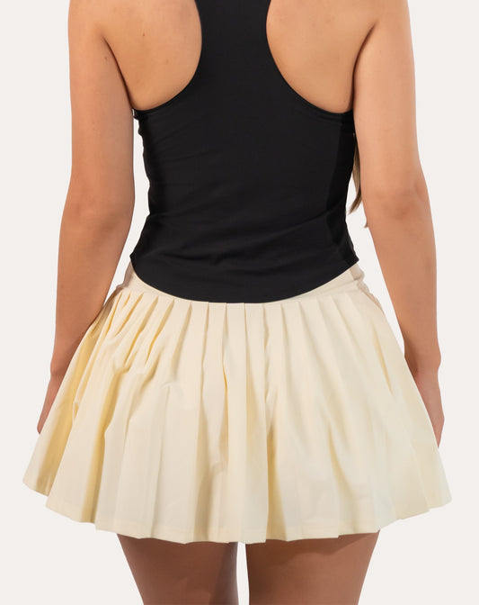 Back close-up of cream tennis skirt showing pleated mini hem and wide high-waist band